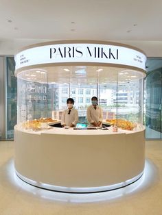 two men standing in front of a display case with food on it's sides