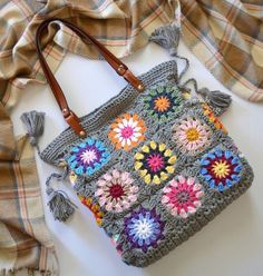 a crocheted purse sitting on top of a table next to a plaid blanket