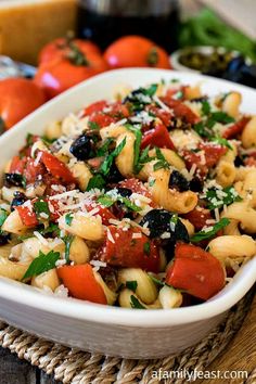 a white bowl filled with pasta salad on top of a wooden table next to an apple