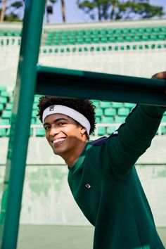 a young man holding a tennis racquet on top of a tennis ball court