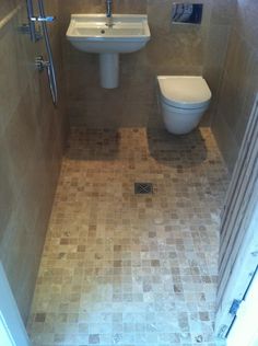 a bathroom with a toilet, sink and shower stall in the middle of it's tiled floor