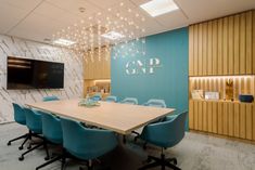 a conference room with blue chairs and a large wooden table in front of a flat screen tv mounted on the wall