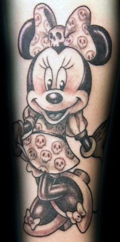 a mickey mouse tattoo with skulls on the leg and skull in his hand, as if he