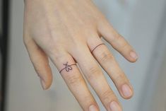 a person's hand with a small tattoo on the middle finger and an arrow in the middle