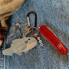 a keychain that has been placed on someone's jean jacket with a red pocket knife