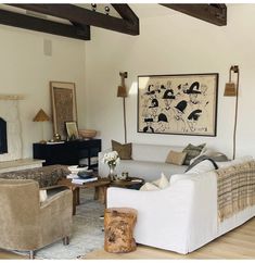 a living room filled with furniture and a painting on the wall above it's fireplace