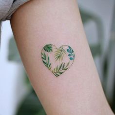 a heart shaped tattoo with green leaves on the back of her left arm and shoulder