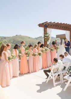 a group of people standing next to each other near a wedding ceremony on top of a hill