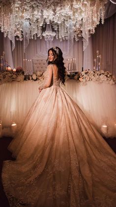 a woman in a wedding dress standing under a chandelier