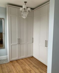 an empty room with white cabinets and wood floors