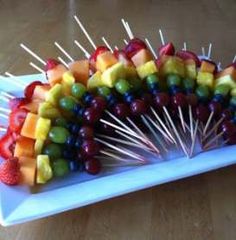 a bunch of skewers filled with fruit on top of a white plate