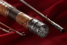 two fishing rods are sitting on a red velvet covered surface with metal handles and hooks