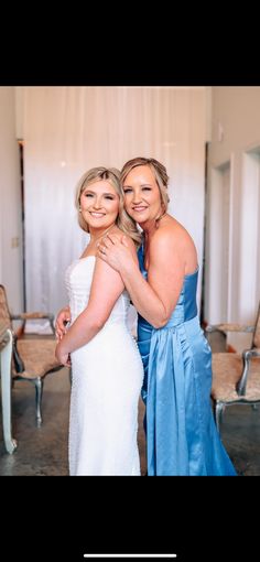 two women in blue dresses hugging each other