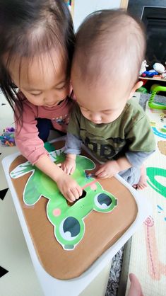 two young children playing with a paper cut out of a dog on a table top