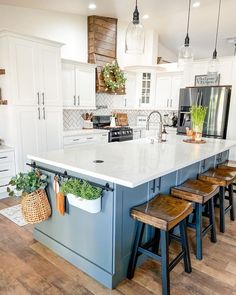 a kitchen island with four stools in front of it and plants on the counter