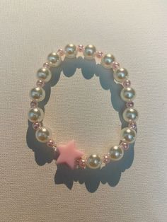 a bracelet with pearls and a pink star