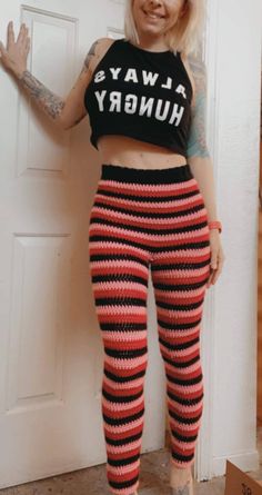 a woman in striped pants and crop top standing next to a door with her arms out