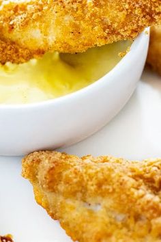 some fried food is in a white bowl on a plate with dipping sauce and bread