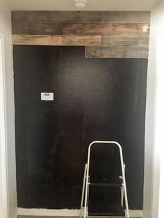 an empty room with a ladder in the corner and a blackboard on the wall