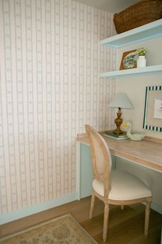 a desk and chair in a room with striped wallpaper on the walls behind it