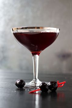 a glass filled with red wine and some black olives