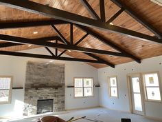 an empty living room with wood beams and stone fireplace