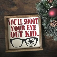 a sign that says you'll shoot your eye out kid next to a christmas tree