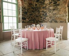 the table is set up with pink linens and white chairs