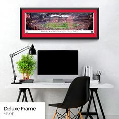 a desk with a computer on it in front of a wall hanging above a chair