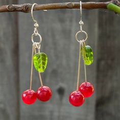 Glass cherry earrings with green leaves Silver-plated dangles  Comes with a silicone backing These stunning cherry earrings are made with translucent beads and are very lightweight. They have silver-plated earring hooks and are hand-made by me, making them the ideal gift to yourself or a loved one!  Jewelry Care: - Keep away from moisture - Put on after applying hair products or lotions - Remove before sleep - Not made for rigorous activity *Stickers included in every order Cherry Dangle Earrings With Ear Wire, Cherry Color Dangle Earrings, Cherry Colored Drop Earrings With Ear Wire, Cherry Drop Earrings With Ear Wire, Beaded Cherry, Earrings Food, Glass Fruit, Diy Jewelry Unique, Cherry Earrings