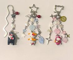 three key chains with charms attached to them on a white surface, one has a hello kitty charm and the other has a cat