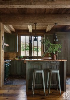 a kitchen with two stools next to an island in the middle of the room