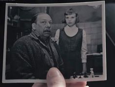 a person holding up an old black and white photo with a child in the background