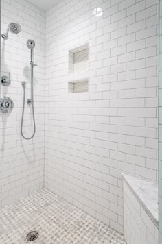 a white tiled bathroom with a shower head and hand held shower faucet in the corner