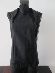 This handmade hybrid jacket is made of woven wool and lined in silk. The front is inspired by perfecto jackets, equipped with a zipper than can be opened from above or below. One side pocket (see pictures).  The back shows a fake hood and a kind of queue evoking a chasuble. The wool color is between dark gray-taupe-brown, and the silk is ivory with gray lines. This is a unique piece of cloth. Fitted Wool Vest Top, Black Sleeveless Wool Top, Fitted Wool Sweater Vest For Winter, Fitted Wool Sweater Vest In Black, Black Wool Vest Outerwear, Fitted Wool Sweater Vest For Fall, Biker Vest, Womens Jackets, Side Pocket