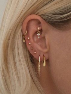 a woman with blonde hair wearing gold ear piercings and diamond earrings on her left ear