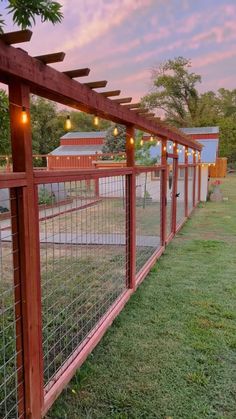 a wooden fence with lights hanging from it's sides and grass in the foreground