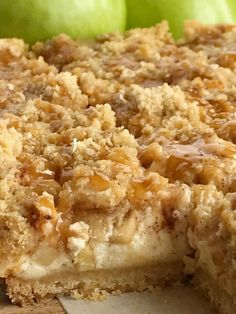 a close up of a pie on a table with two green apples in the background