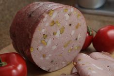 sliced ham, tomatoes and garlic on a cutting board next to a pepper shaker