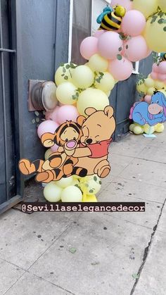 winnie the pooh balloon arch on sidewalk next to building with balloons in front of it