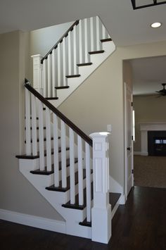 a white stair case in a house with wood floors and ceiling fan on the wall