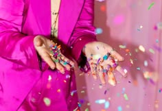 a woman in a pink suit holding her hands out with confetti on it