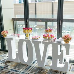 a table topped with cupcakes and pastries next to a large love sign