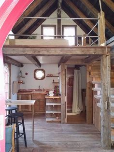 the inside of a small cabin with wooden floors and stairs leading up to an upper floor