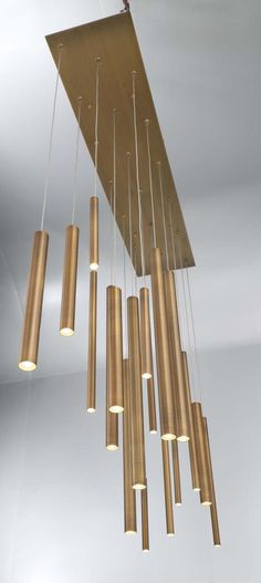 a chandelier made out of brass tubes hanging from the ceiling