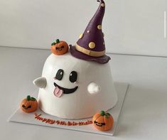 a white cake decorated with pumpkins and a witch's hat