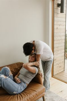 two people are hugging on a couch in the living room