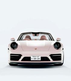 the front view of a pink porsche sports car with two people in it's seat