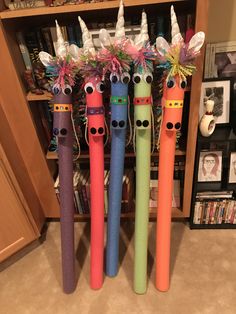 four different colored toothbrushes with unicorns on them in front of a bookcase