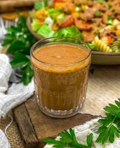 a close up of a bowl of food with salad in the background and dressing in a glass jar